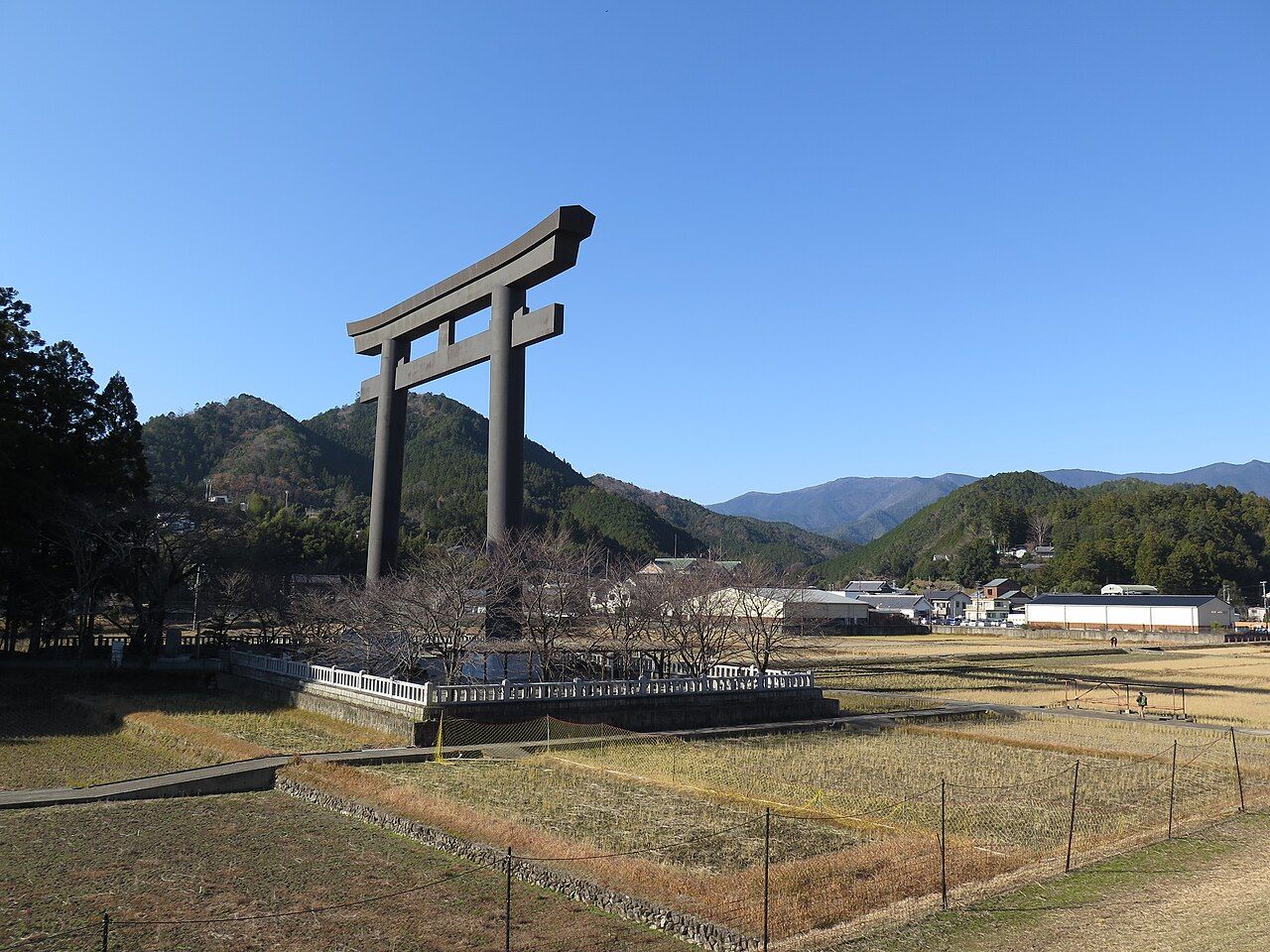 The world's largest torii gate (33.9 m) rising over the Oyunohara sandbank at Kumano Hongu Taisha, with the surrounding Hongu valley and mountains