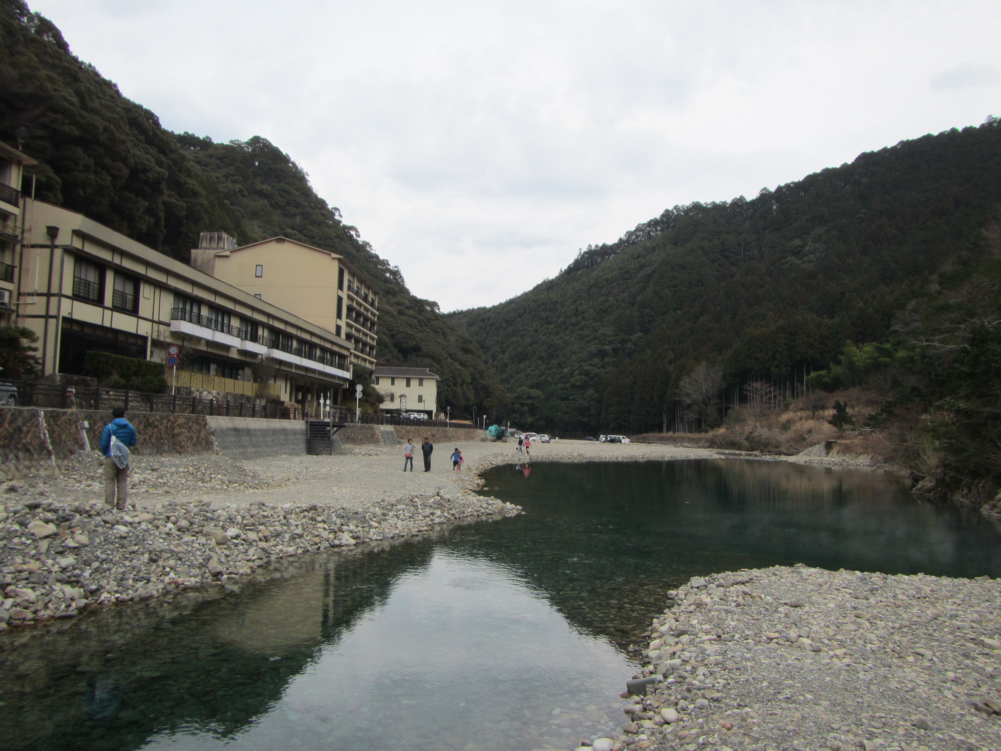 The riverside at Kawayu Onsen in cold-season light, inns above the gravel riverbed where the Kumano Kodo descends