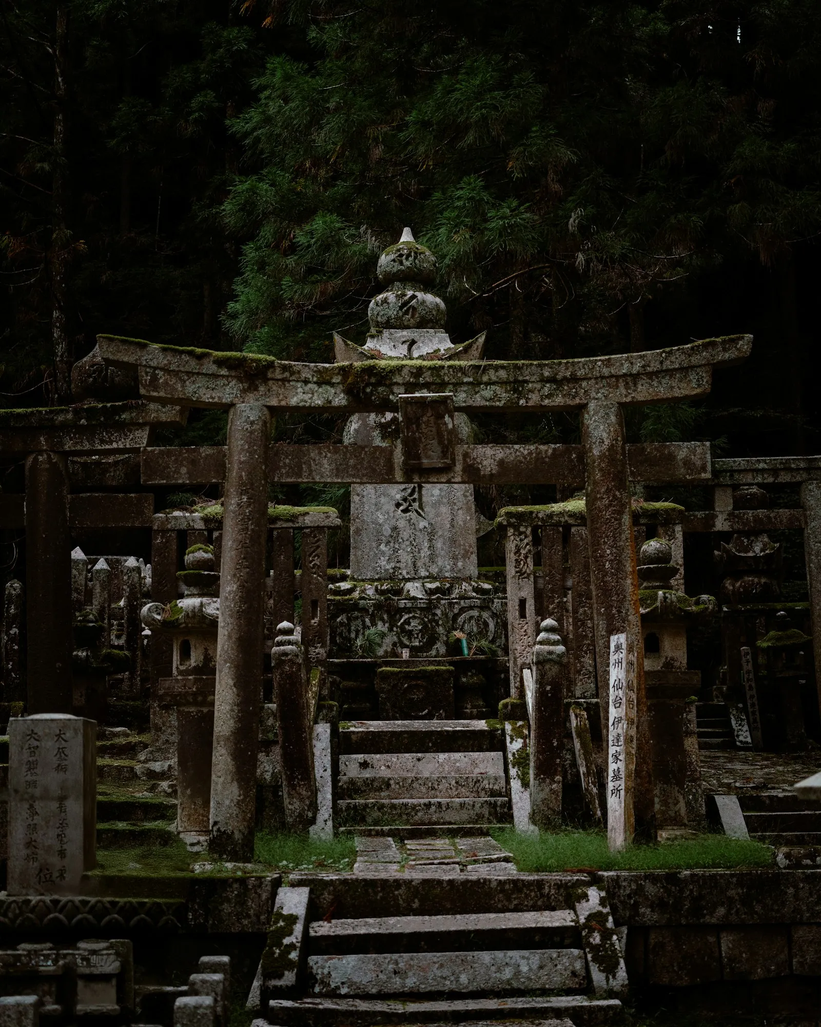 A stone statue among moss-covered graves in the Okunoin cemetery, Koyasan
