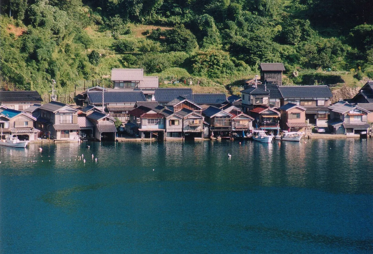 The wooden funaya boathouses of Ine village lined along Ine Bay, reflected in turquoise water