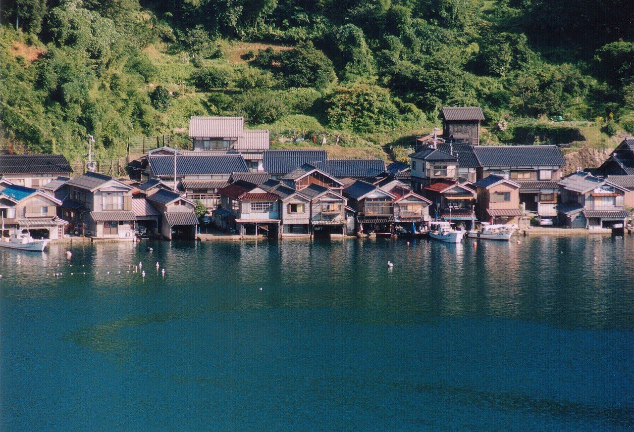 The wooden funaya boathouses of Ine village lined along Ine Bay, reflected in turquoise water