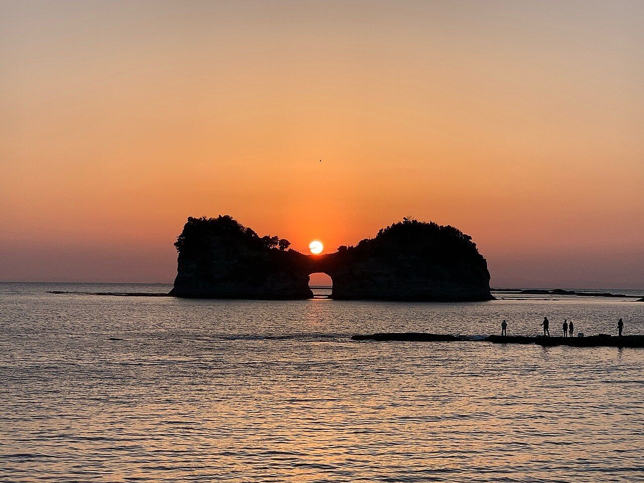 The sun setting through the natural sea-arch of Engetsu Island off Shirahama, on Wakayama's Pacific coast